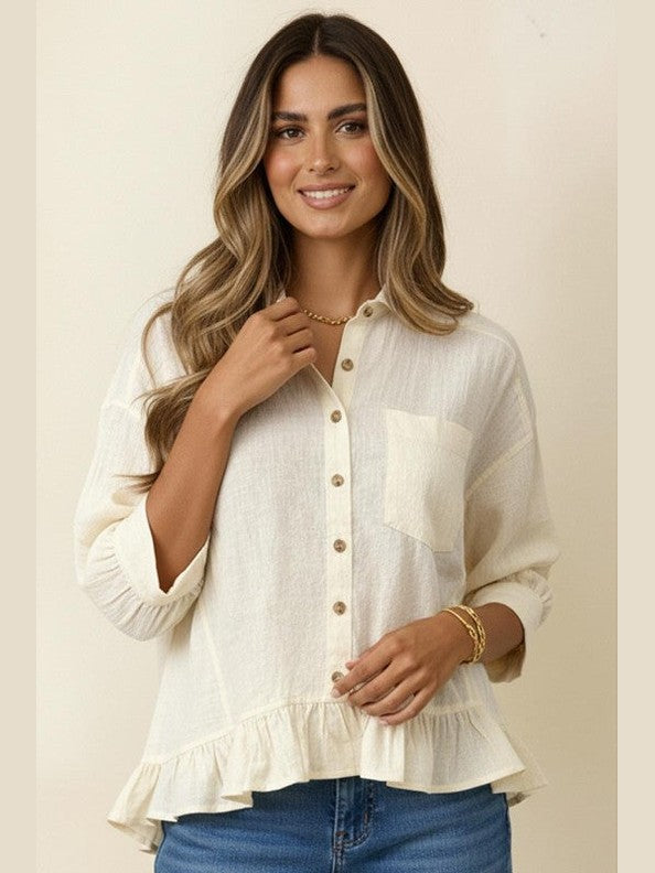 Woman wearing a beige blouse with ruffled sleeves and blue jeans on a beige background