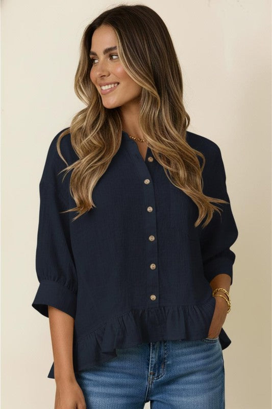 Woman wearing a navy blue blouse with buttons and blue jeans on a beige background