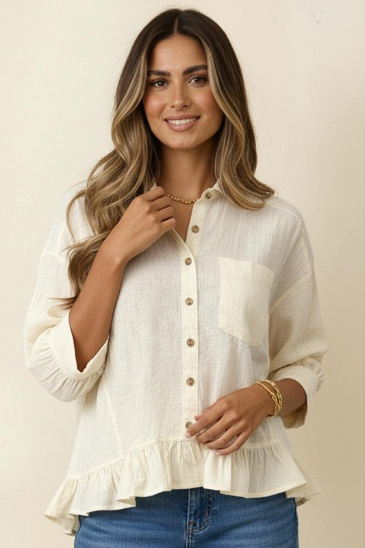 Woman wearing a beige blouse with ruffled sleeves and blue jeans on a beige background
